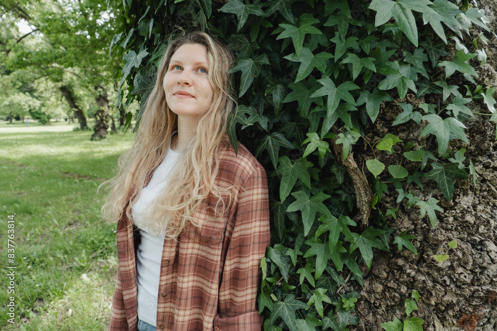 Smiling woman standing near tree trunk in park Smiling woman standing near tree trunk in park