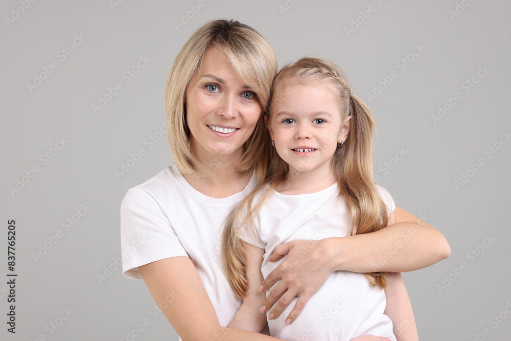 Family portrait of happy mother and daughter on grey background Family portrait of happy mother and daughter on grey background