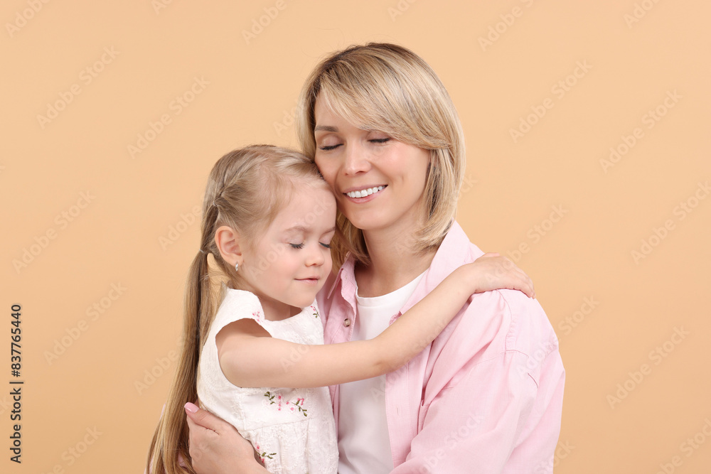 Daughter hugging her happy mother on beige background Daughter hugging her happy mother on beige background