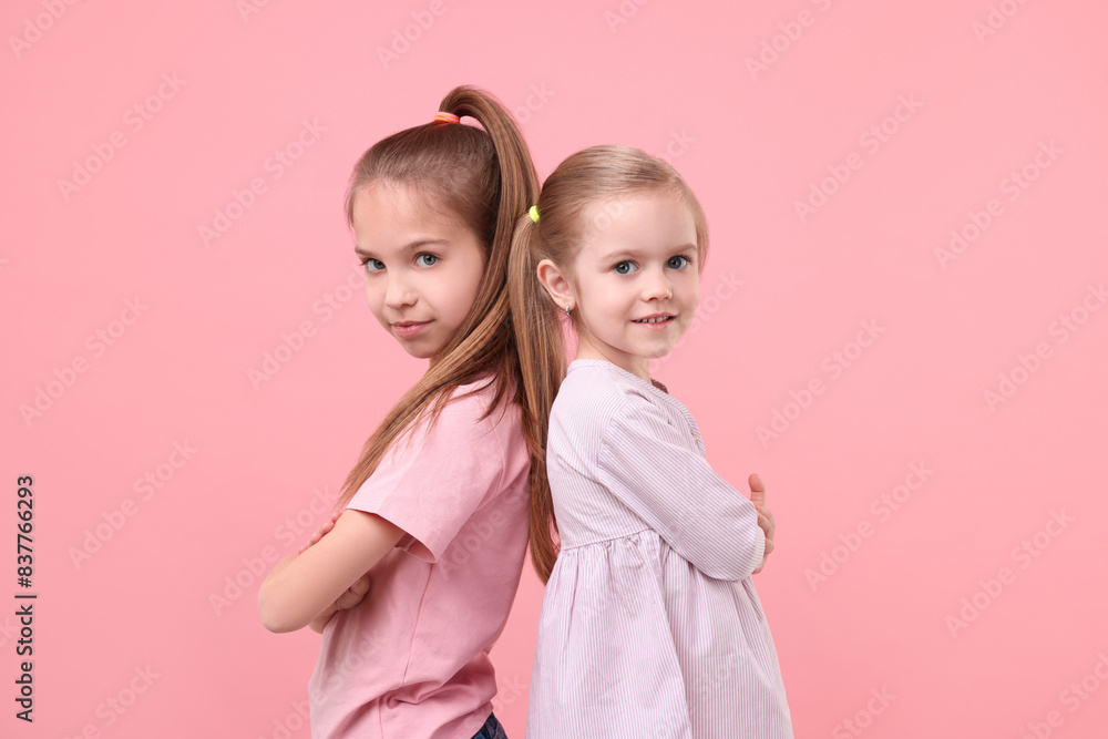 Portrait of cute little sisters on pink background Portrait of cute little sisters on pink background