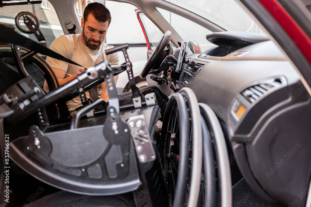 Disabled man adjusting parts of handcycle sitting in car Disabled man adjusting parts of handcycle sitting in car