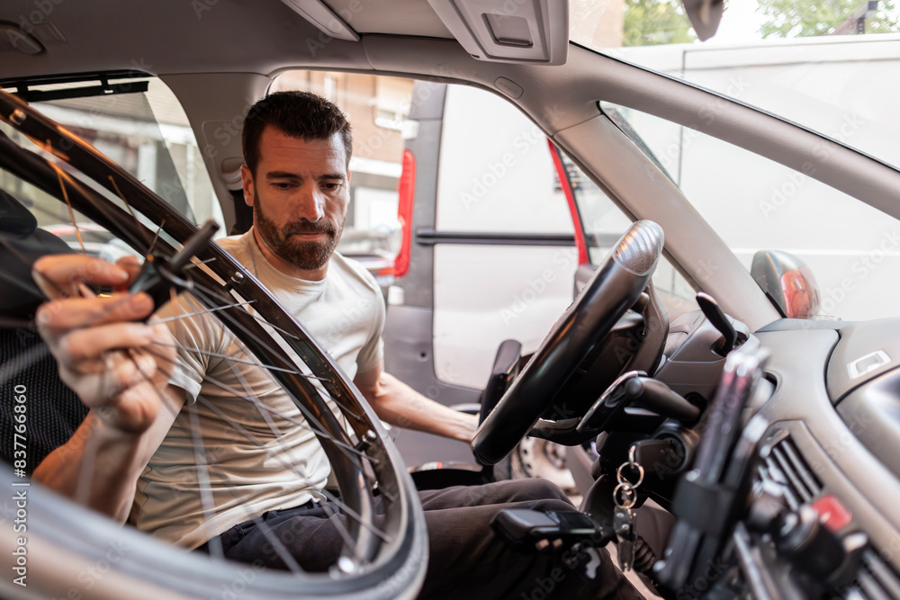 Disabled man holding cycle wheel sitting in car Disabled man holding cycle wheel sitting in car