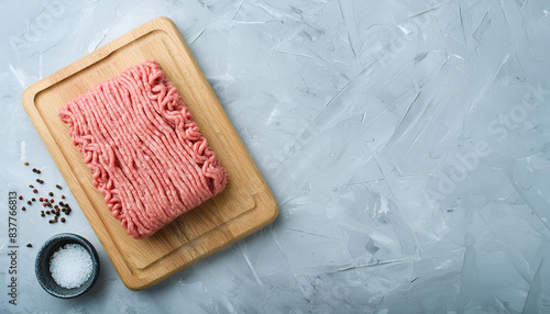 Raw minced meat on wooden board with rosemary sprigs and spices. Preparation for cooking. Top view