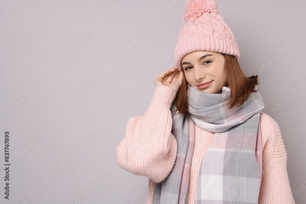 Beautiful woman in warm scarf and hat on gray background, space for text Beautiful woman in warm scarf and hat on gray background, space for text