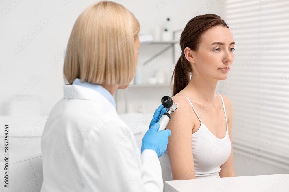 Dermatologist with dermatoscope examining patient in clinic Dermatologist with dermatoscope examining patient in clinic