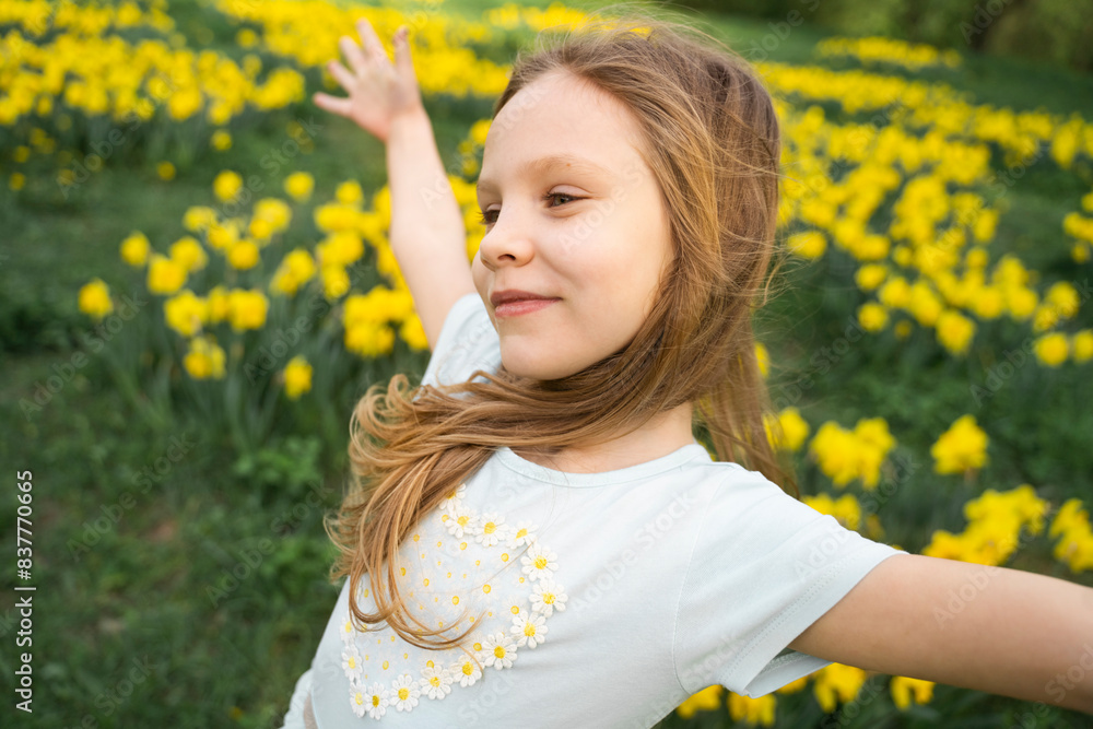 Smiling cute girl standing with arms outstretched in daffodil field Smiling cute girl standing with arms outstretched in daffodil field