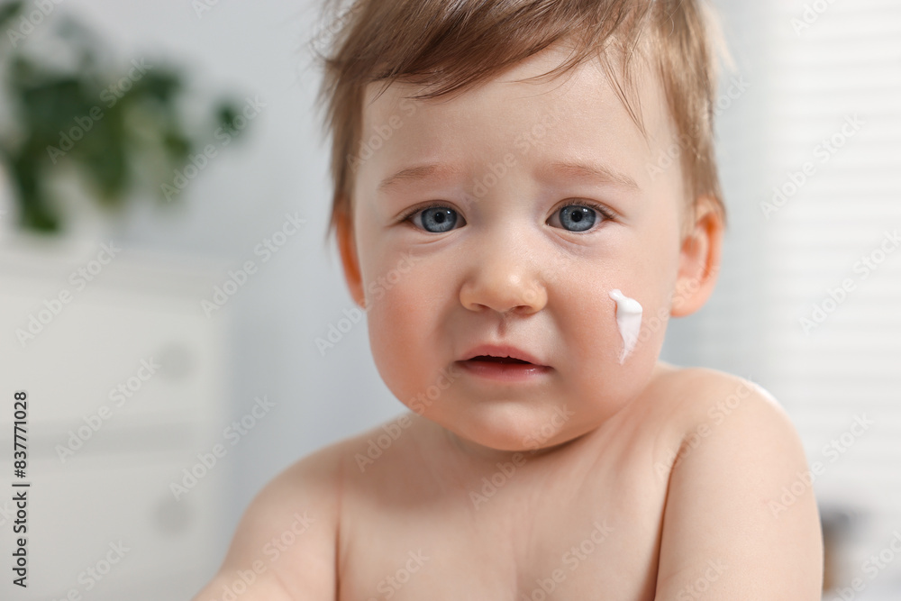 Cute little baby with moisturizing cream on face indoors Cute little baby with moisturizing cream on face indoors