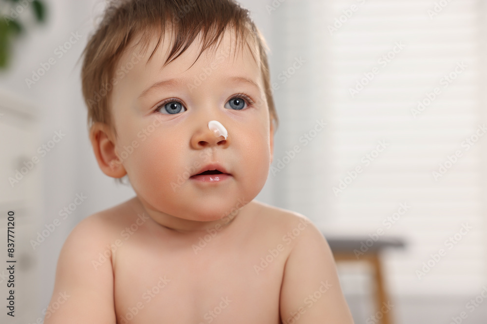 Cute little baby with moisturizing cream on face indoors Cute little baby with moisturizing cream on face indoors