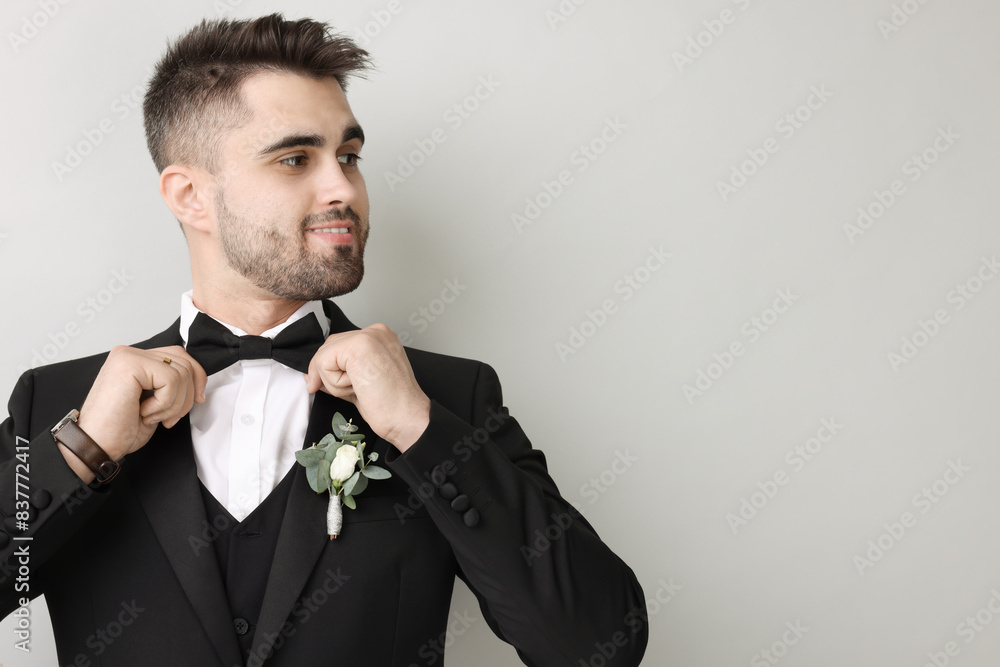 Handsome young groom with boutonniere on light grey background, space for text. Wedding accessory Handsome young groom with boutonniere on light grey background, space for text. Wedding accessory