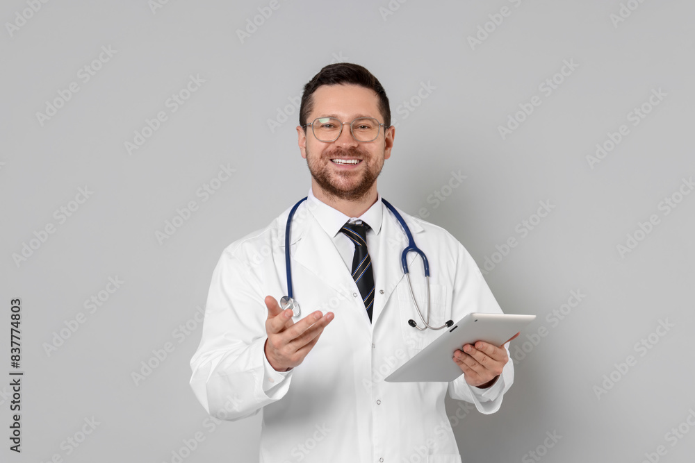 Portrait of smiling doctor with tablet on light grey background Portrait of smiling doctor with tablet on light grey background