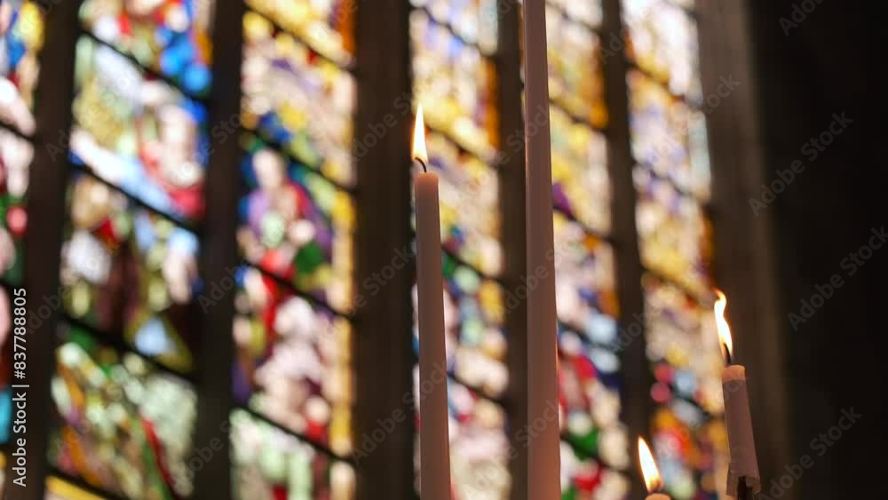 Candles burning in front of stained glass windows in a church Candles burning in front of stained glass windows in a church