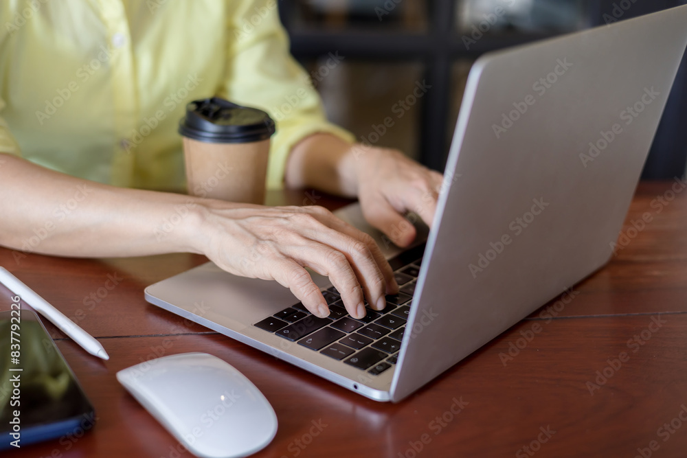 Business women in a yellow shirt working on laptop in office Business women in a yellow shirt working on laptop in office
