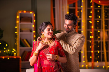 Indian husband presenting gold necklace to wife on diwali festival celebration
