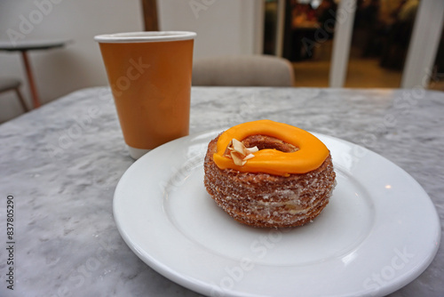 Close up Cronut (combination of croissant and doughnut) Topped with Passion fruit jam and toasted coconut Ganache served with Blooming marshmallow on hot chocolate drink photo