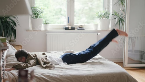 Young man falling onto his bed after a long day photo
