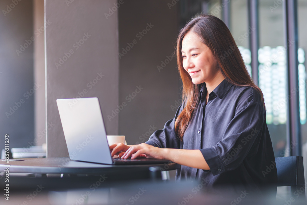 Portrait image of a young woman working and typing on laptop computer in cafe Portrait image of a young woman working and typing on laptop computer in cafe