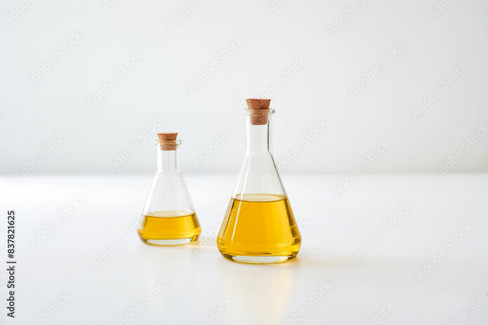 Two Glass Bottles with Cork Stoppers Filled with Golden Liquid on a White Background Two Glass Bottles with Cork Stoppers Filled with Golden Liquid on a White Background