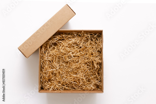 Open; box with shredded paper on a white background.; Cardboard box with decorative fillers for your product. Flat lay; top view; empty space for products