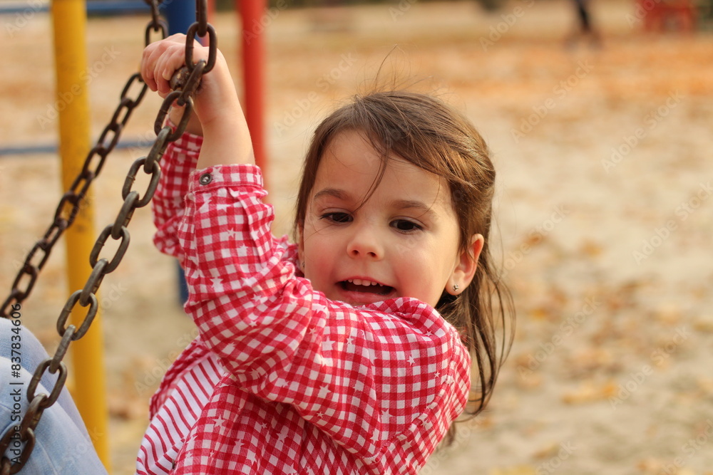 A little beautiful girl in a flat T-shirt and a plaid shirt enjoys playing in the autumn park. The concept of children's happiness in nature. Bright explosion of colors A little beautiful girl in a flat T-shirt and a plaid shirt enjoys playing in the autumn park. The concept of children's happiness in nature. Bright explosion of colors