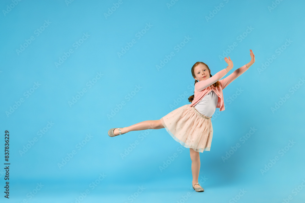 Cute little girl dancing on light blue background, space for text Cute little girl dancing on light blue background, space for text