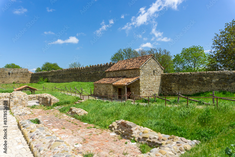 Courtyard of Samtavisi Cathedral. Ruins of old building, stone wall, small church, green grass. Courtyard of Samtavisi Cathedral. Ruins of old building, stone wall, small church, green grass.