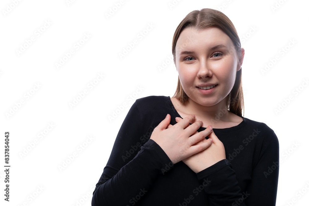 A school-age girl with brown hair holds her hands to her heart A school-age girl with brown hair holds her hands to her heart