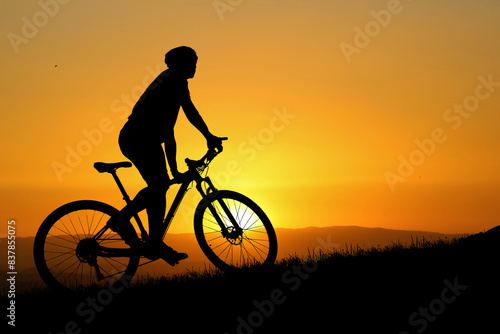 Silhouette of a Cyclist Riding a Mountain Bike at Sunset with a Vibrant Orange Sky in the Background, Capturing the Essence of Outdoor Adventure and Freedom © STOCK PHOTO 4 U
