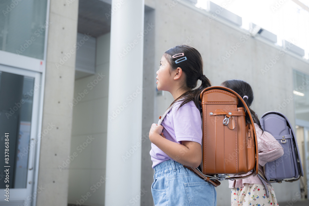 Elementary school students looking up with school bags on their backs Faceless back view