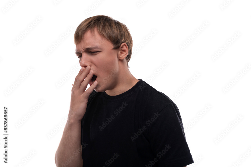 A handsome young man with blond hair dressed in a black T-shirt is tired and yawns A handsome young man with blond hair dressed in a black T-shirt is tired and yawns