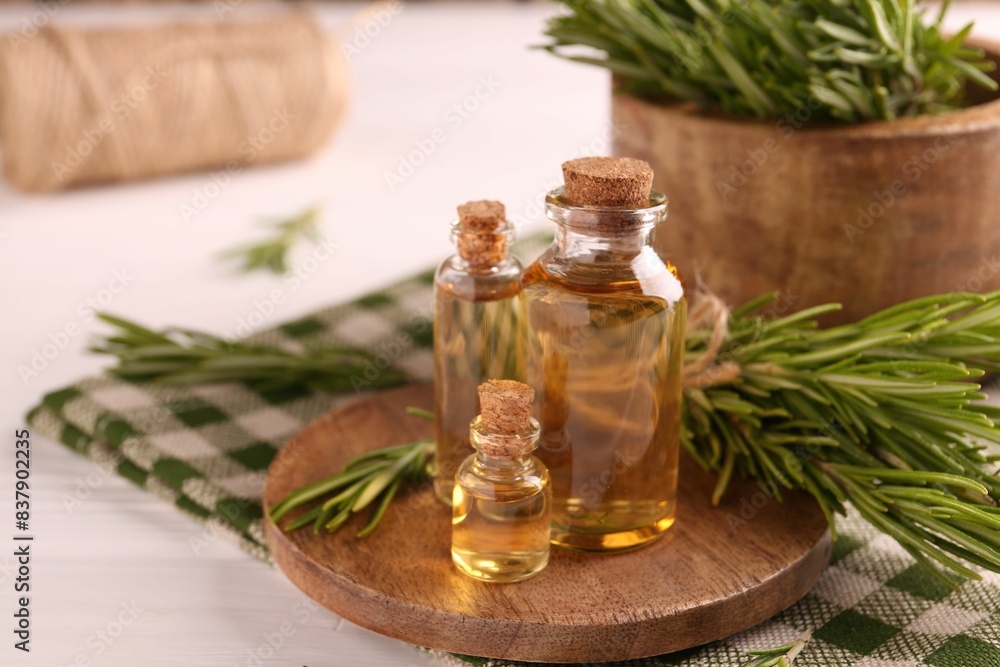 Essential oil in bottles and rosemary on white wooden table Essential oil in bottles and rosemary on white wooden table