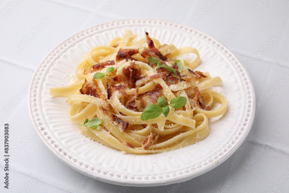 Tasty pasta with bacon and basil on white tiled table Tasty pasta with bacon and basil on white tiled table