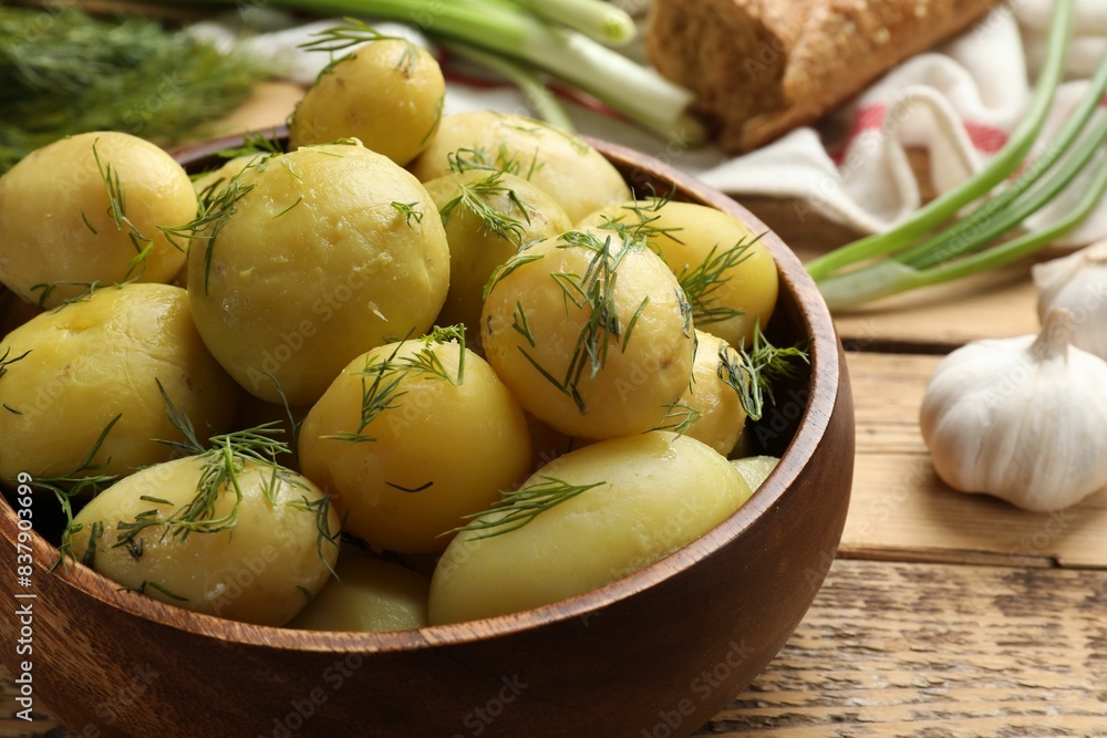 Tasty young boiled potatoes with dill in bowl on wooden table, closeup Tasty young boiled potatoes with dill in bowl on wooden table, closeup