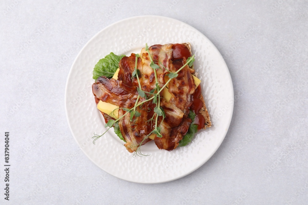 Tasty sandwich with bacon and microgreens on light grey table, top view Tasty sandwich with bacon and microgreens on light grey table, top view