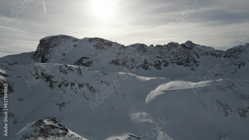 Drone shot of snowy mountains and ski slopes of Tignes in the French alps with a sunny cloudy sky