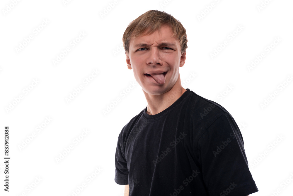 Cute teenage guy with blond hair dressed in a black T-shirt makes a face Cute teenage guy with blond hair dressed in a black T-shirt makes a face