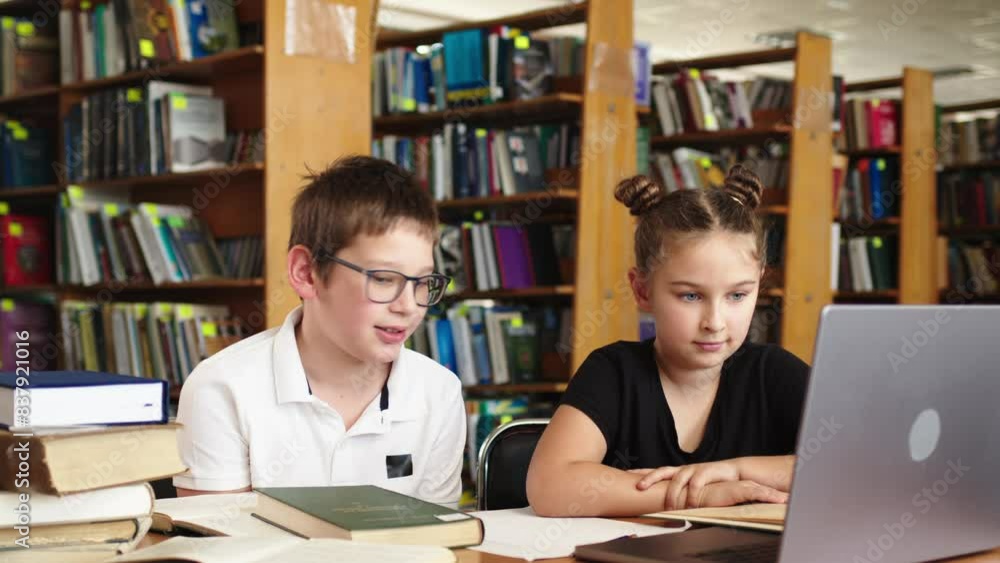 A group of schoolchildren in an out-of-class lesson. Children read books and study in the library. Concept of learning, knowledge and teamwork. A group of schoolchildren in an out-of-class lesson. Children read books and study in the library. Concept of learning, knowledge and teamwork.
