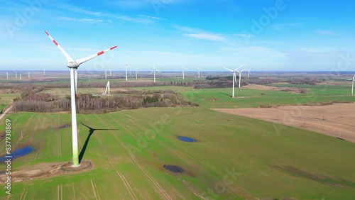 Aerial footage of wind turbines in a wind farm generating green electric energy on a wide green field on a sunny day, in Taurage, Lithuania photo