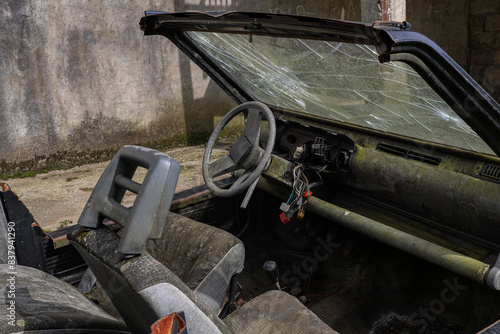 steering wheel, seats  of a abandoned cabriolet car. Dirty and worn off vintage classic vehicle interior. Interior view of the dash board of an old junked retro aged automobile in a junkyard.