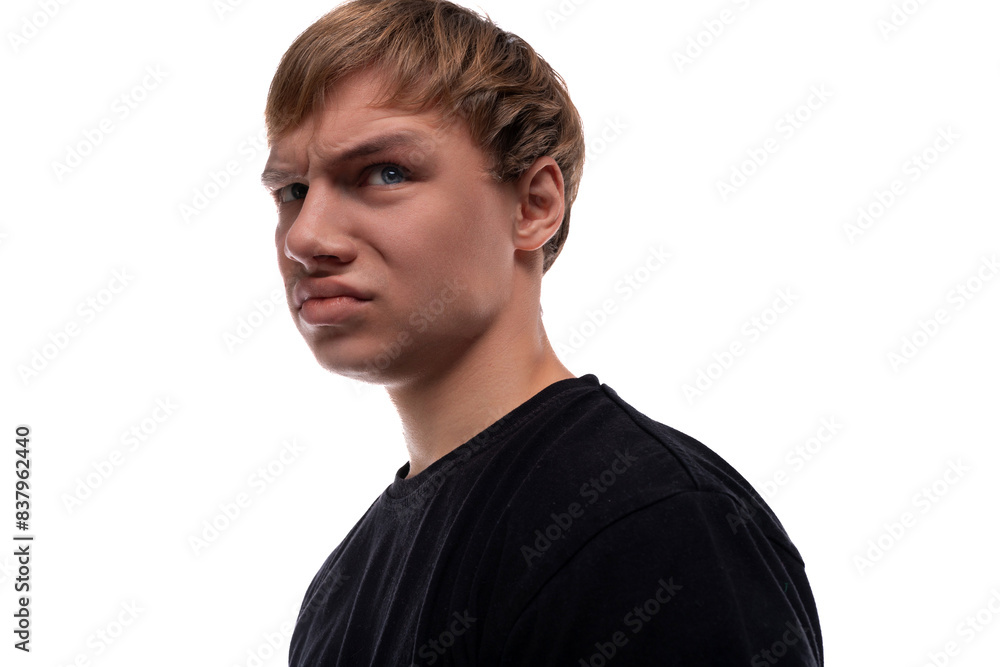 Offended teenage guy with blond hair dressed in a black T-shirt Offended teenage guy with blond hair dressed in a black T-shirt