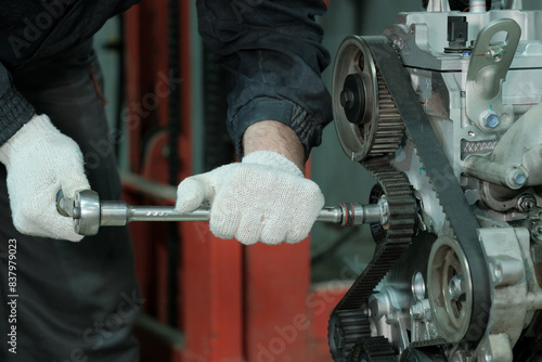 Car engine repair at the service center. An auto mechanic performs work on replacing the timing belt. photo