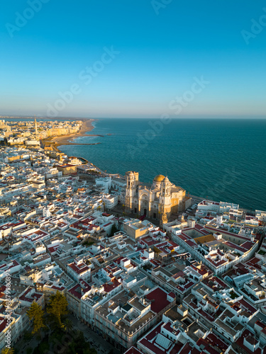 Aerial view of Cadiz city at sunset. City center with spectacular Cathedral of Cadiz in the middle. Medieval and historic city. Famous travel destination. Atlantic Ocean in background. Vertical photo