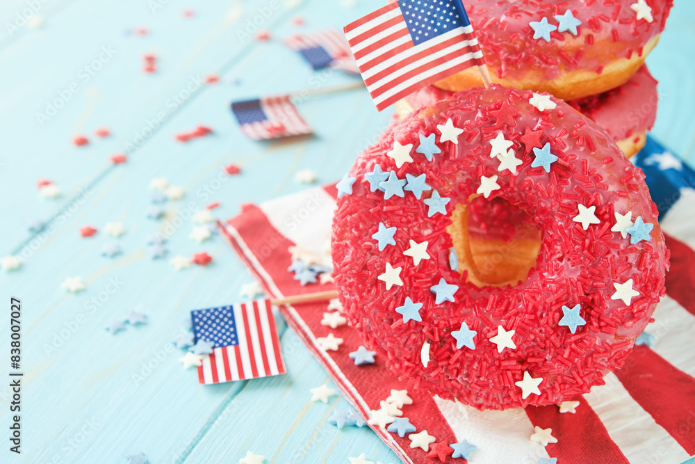 Obraz premium Patriotic sweet donuts 4th july with american flag. Delicious american donuts with red icing and blue and red stars toping on blue background. Dessert food for American Independence Day celebration.