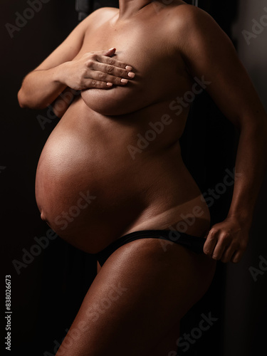 Pregnant woman pulls back her panties showing instant tan. Vertical photo. 