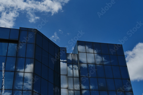 A glass skyscraper with clouds reflected as if in a mirror. An office building with many floors. A small town in Serbia - Zrenjanin. Vojvodina District.