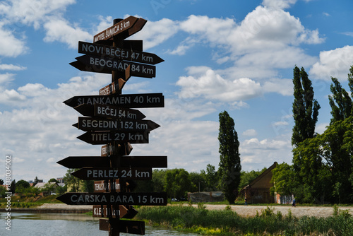 A sign with wooden arrows indicating the directions of different cities in Serbia. The embankment of the river in the city of Zrenjanin, Vojvodina district. photo