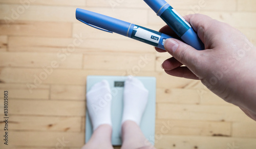  Ozempic Insulin injection pen for diabetics and weight loss. Woman weighs herself and holds Ozempic in her hand.