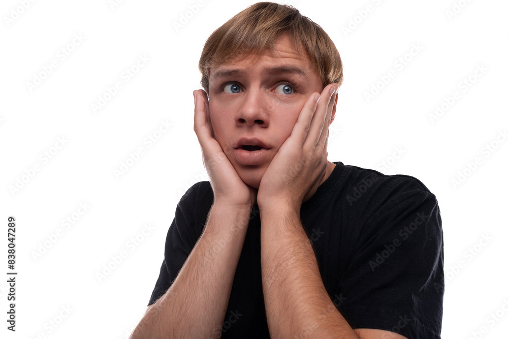 Handsome Caucasian blond teenager guy in a black T-shirt is worried and wants to hide Handsome Caucasian blond teenager guy in a black T-shirt is worried and wants to hide