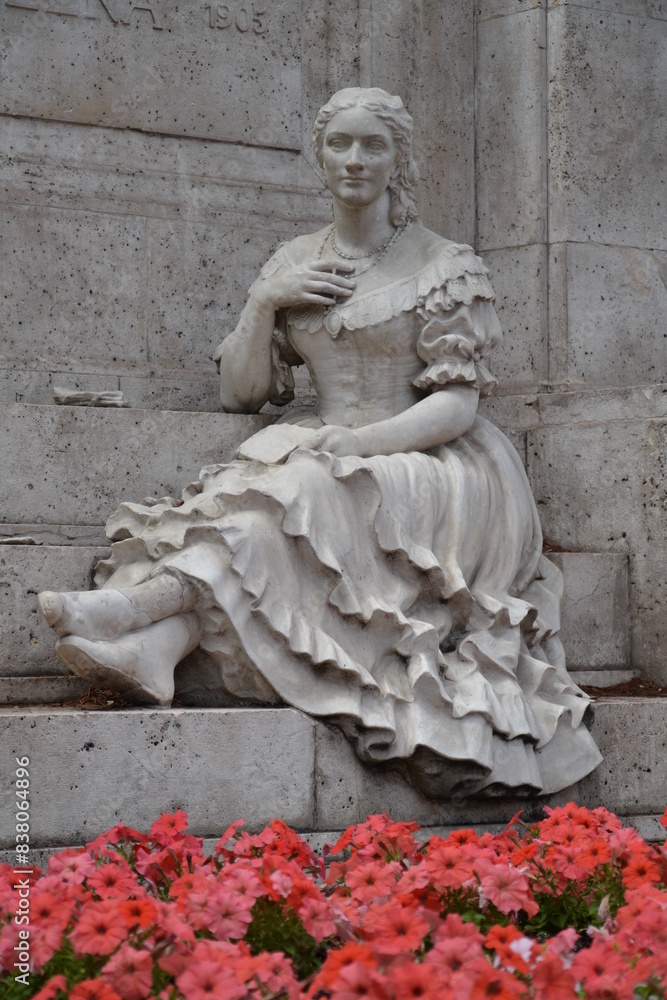 Obraz premium Madrid, espagne, 14 aout 2015 : statue de femme assise derrière un parterre de fleurs roses, place de Colomb, Madrid