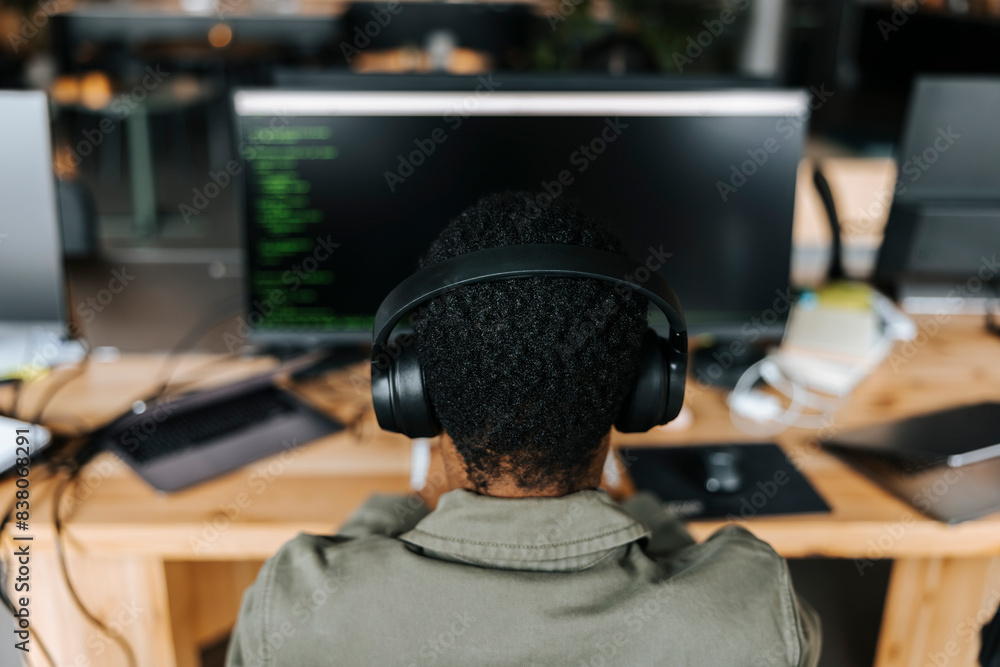 High angle view of male computer programmer wearing headphones and coding at office High angle view of male computer programmer wearing headphones and coding at office