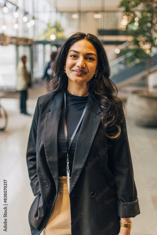 © Maskot - Portrait of smiling young female entrepreneur standing with hand in pocket at convention center © Maskot - Portrait of smiling young female entrepreneur standing with hand in pocket at convention center